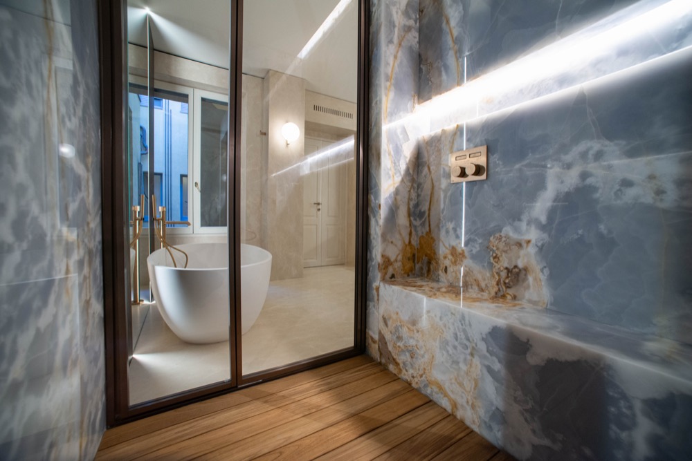 View from inside the walk-in shower, looking through glass towards a freestanding bath