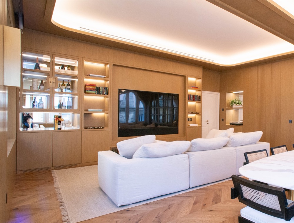 Living room with a sofa, television, bookshelves and a glass drinks cabinet